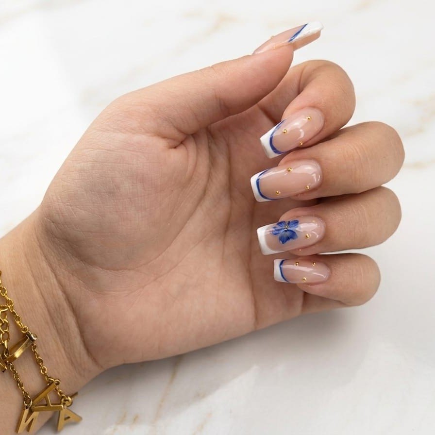Francesa blanca cuadrada con linea azul, una flor azul y detalles dorados